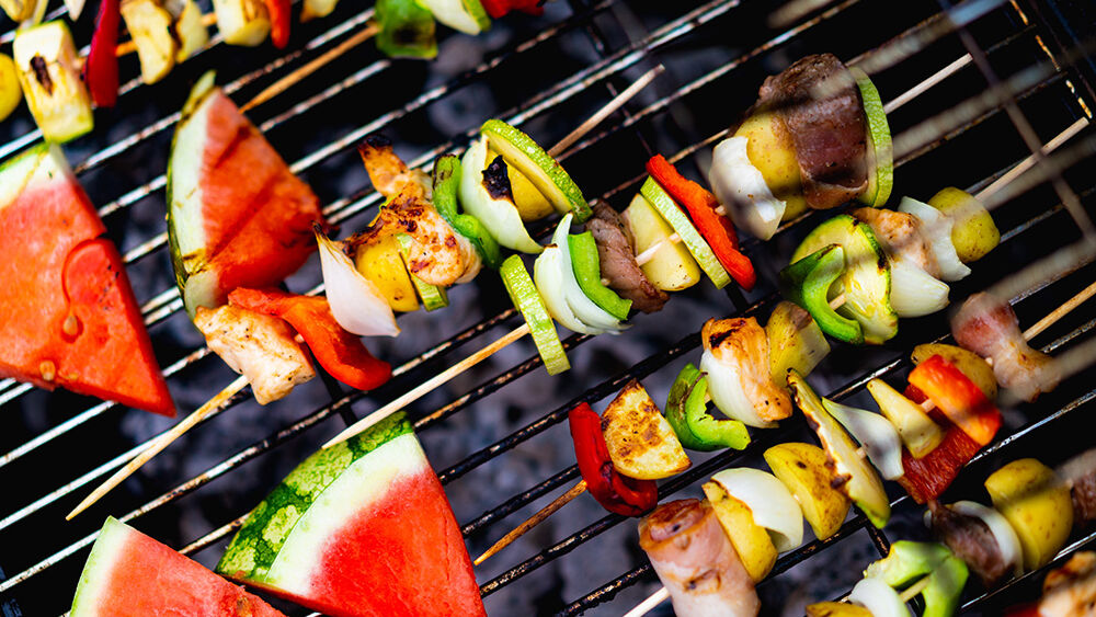Gemüsespieße und Melone liegen auf einem Grill nachhaltig-grillen