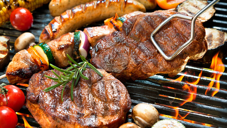Steaks, Würstchen und Gemüse auf dem Grillrost Fleisch grillen